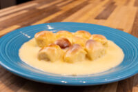 Eight golden buns coated in pale vanilla custard, Little Buns with Vanilla Pudding on a blue plate.