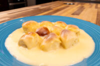 Little Buns with Vanilla Pudding (Buchticky s Krémem) sitting in pale custard sauce on a blue plate