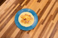 Little Buns with Vanilla Pudding (Buchticky s Krémem) served on a blue ridged plate, small golden buns sitting in a pool of pale custard