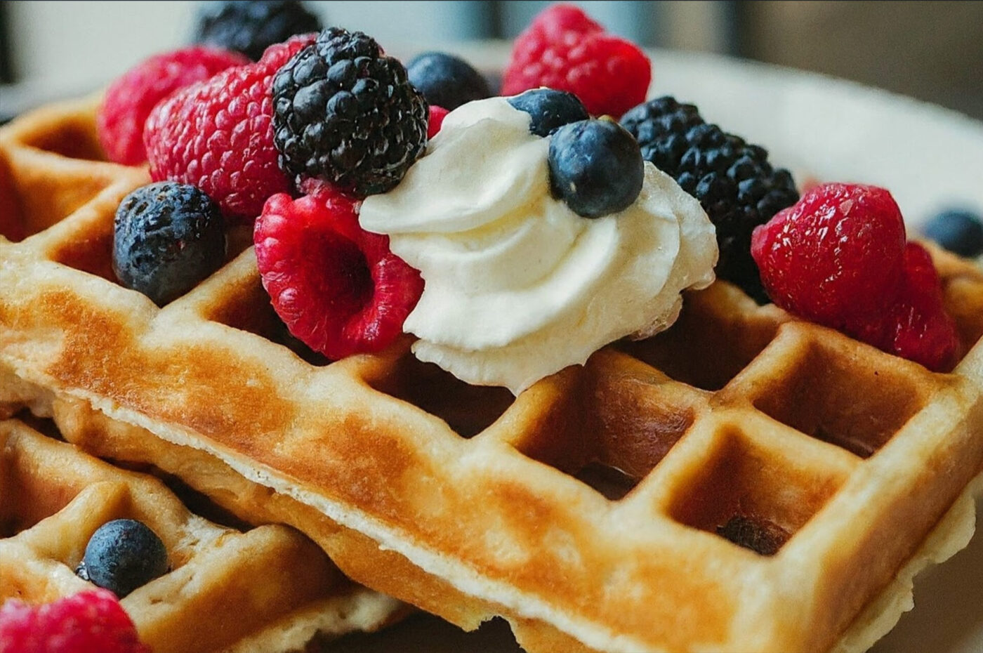 A square Belgian-style Waffle topped with whipped cream, raspberries, blueberries, and blackberries.