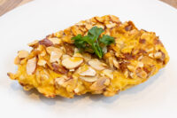 Almond Chicken Schnitzel with sliced almond crust and parsley garnish on a white plate