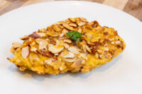 Almond Chicken Schnitzel with a crispy sliced-almond crust and parsley garnish on a white plate