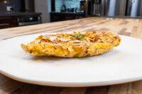 Golden Almond Chicken Schnitzel topped with sliced almonds and herb garnish on a white plate