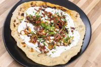 Lokše Flat Bread with Bryndza Cheese Substitute and Bacon, topped with white cheese sauce, bacon, and herbs