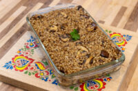 Baked Mushroom Kuba (Houbovy Kuba) with mushroom slices and parsley in a glass dish on a folk-painted board.