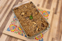 Baked Mushroom Kuba (Houbovy Kuba) with mushroom slices and parsley in a glass dish on a painted board.