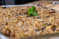 Baked Mushroom Kuba (Houbovy Kuba) in a metal tray with mushrooms, onions, and a parsley garnish.