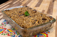 Baked Mushroom Kuba (Houbovy Kuba) with barley and mushrooms in a glass dish, garnished with herb sprig