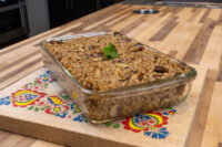Baked Mushroom Kuba (Houbovy Kuba) with mushroom pieces and parsley in a glass dish on a floral trivet.