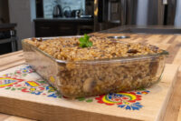 Baked Mushroom Kuba (Houbovy Kuba) in a glass dish, topped with parsley, on a painted wooden board.