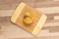 A single round Pagáče (Pagache) with Cracklings topped with seeds, on a wooden board.