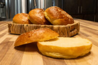 Burger Buns Golden Burger Buns with sesame seeds in a woven basket, one sliced open showing soft interior