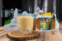 Glass of Czech Egg Liqueur – Czech Eggnog on a wooden slice, with a nativity decoration behind