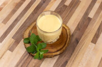 Glass of Czech Egg Liqueur – Czech Eggnog on a wooden slice, garnished with fresh mint leaves.