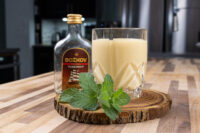Glass of Czech Egg Liqueur – Czech Eggnog garnished with mint, beside a bottle of Božkov Tuzemský rum