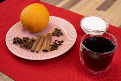 Orange, cinnamon, star anise and cloves on a plate with sugar and a glass of Czech Mulled Wine Svarak.