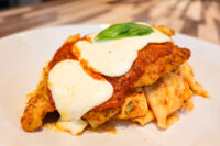 Breaded Chicken Parmesan topped with marinara, melted mozzarella, and basil, plated over pasta