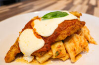 Breaded Chicken Parmesan topped with marinara sauce, melted mozzarella, and basil, served over rigatoni pasta