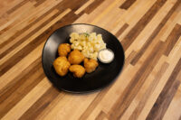 Plate of Fried Cauliflower Smažený Květák with diced potatoes and a white dipping sauce on wood table.