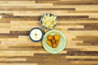Golden fried Cauliflower Smažený Květák bites on a green plate beside a dip and diced side dish.