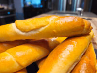 Close-up of golden, glossy Czech Rolls Rohliky piled together, showing their shiny baked crust.