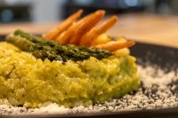 Plated Asparagus Risotto with Shrimp topped with asparagus spears, shrimp tails, and grated cheese.