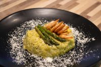 Plated Asparagus Risotto with Shrimp topped with grilled shrimp and asparagus spears, dusted with parmesan.