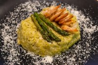 Plated Asparagus Risotto with Shrimp topped with grilled shrimp and asparagus spears, dusted with parmesan.