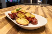 Halved red and yellow baby potatoes with butter, pepper, and herb garnish on a white oval plate.