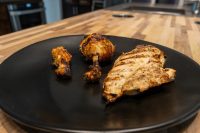 Grilled Lemon and Garlic Chicken drumsticks and breast piece with char marks on a black plate