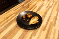 Grilled Lemon and Garlic Chicken drumsticks and breast with char marks on a black plate