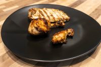 Grilled Lemon and Garlic Chicken pieces with charred marks served on a black plate