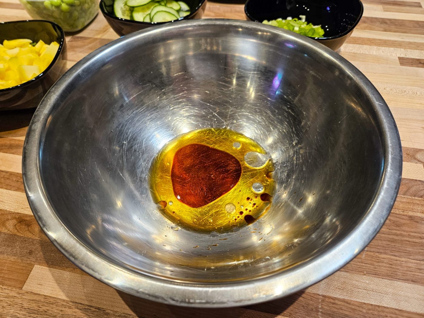 Steel bowl with oil and dark marinade pooled at the bottom, for Poke Bowl with Salmon.