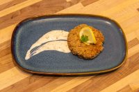 Tuna Cakes Breaded Tuna Cake topped with lemon slice and parsley, served with creamy sauce on a blue plate