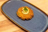 Tuna Cakes Golden fried Tuna Cake topped with a lemon slice and parsley, served on a blue ceramic plate.
