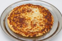 A whole 60 min. Pan Pizza with bubbly browned cheese and thick crust on a metal pan.