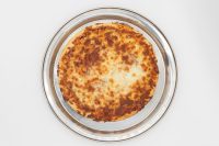 Overhead shot of 60 min. Pan Pizza with browned melted cheese on a round metal pan