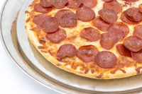 Baked 60 min. Pan Pizza with pepperoni and melted cheese on a round metal tray.