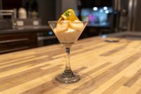 Shrimp Cocktail in a martini glass with creamy sauce and a citrus peel garnish, set on a wooden counter.