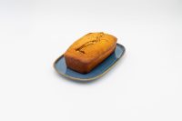 A golden-brown loaf of Banana Bread with a split top, resting on a blue rectangular plate.