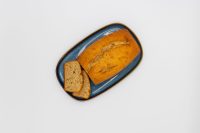 Sliced Banana Bread loaf with golden crust on a dark blue oval plate against white background.