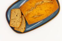 Sliced Banana Bread loaf on a blue ceramic platter, two slices cut and laid beside the rest.
