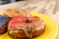 Glazed Donuts and Donut Holes on a yellow plate, one topped with red and green sugar sprinkles.