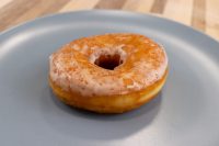 A single glazed ring donut from a Donuts and Donut Holes recipe, resting on a grey plate.