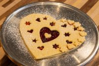 Heart-shaped Linzer Tart Hearts with cut-out stars and hearts showing red jam, dusted with powdered sugar.