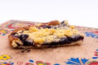 Cross-section slice of Sheet Kolach with Streusel showing dark berry filling and golden streusel on a wooden board.