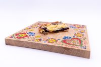 A slice of Sheet Kolach with Streusel showing dark berry filling and crumble topping on a painted wooden board.