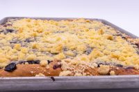 Sheet Kolach with Streusel in a metal pan, golden streusel crumbs covering dark berry filling at the edges.