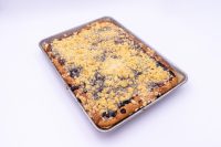 Baked Sheet Kolach with Streusel showing golden crumb topping and dark berry filling peeking through, on a metal tray.