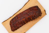 Whole slab of American BBQ – Honey Pork Ribs with a charred, caramelized crust on a wooden board